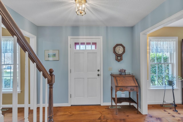 entrance foyer featuring wood finished floors, a wealth of natural light, baseboards, and stairway
