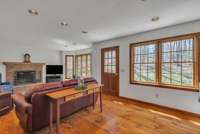 living room with visible vents, baseboards, recessed lighting, a fireplace, and wood-type flooring