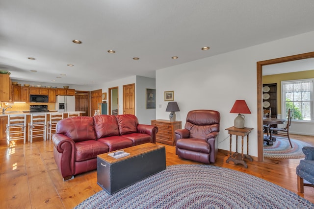 living room with recessed lighting, light wood-type flooring, and baseboards