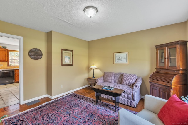living area featuring light wood-style floors, a textured ceiling, and baseboards