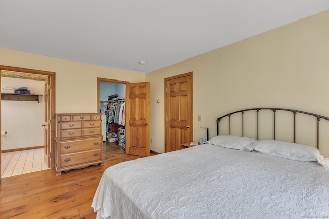 bedroom with light wood-style flooring, baseboards, a closet, and a walk in closet