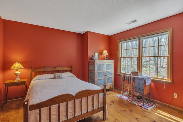 bedroom featuring hardwood / wood-style floors, baseboards, and visible vents