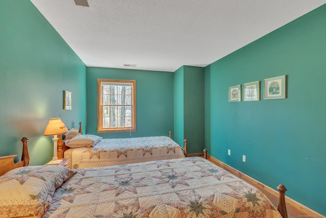 bedroom featuring a textured ceiling, visible vents, and baseboards