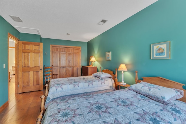 bedroom with a closet, baseboards, visible vents, and hardwood / wood-style flooring
