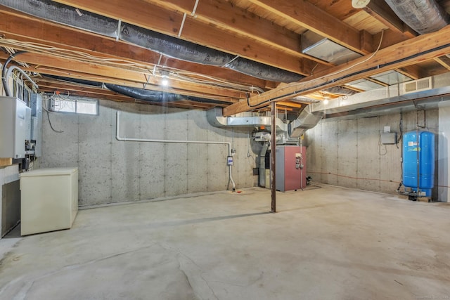 basement featuring heating unit, visible vents, and fridge