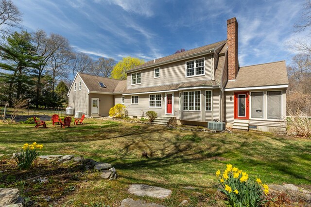 rear view of house featuring central air condition unit, a yard, entry steps, and a chimney