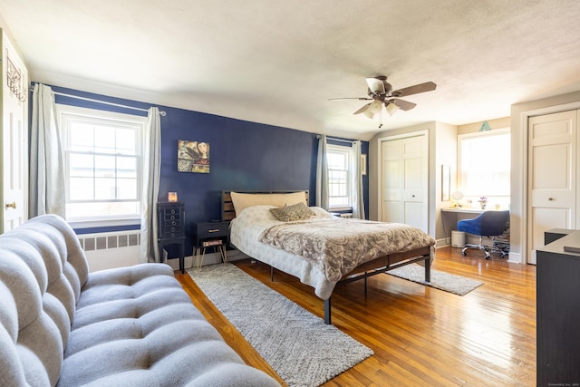 bedroom featuring baseboards, ceiling fan, two closets, and hardwood / wood-style floors