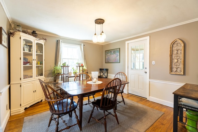 dining space featuring crown molding, baseboards, and wood finished floors