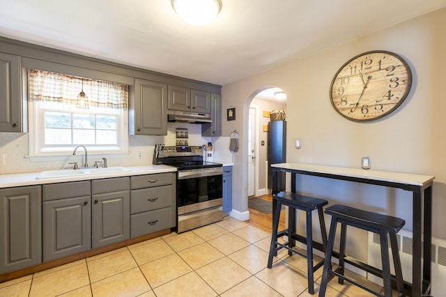 kitchen with arched walkways, a sink, gray cabinetry, electric stove, and under cabinet range hood