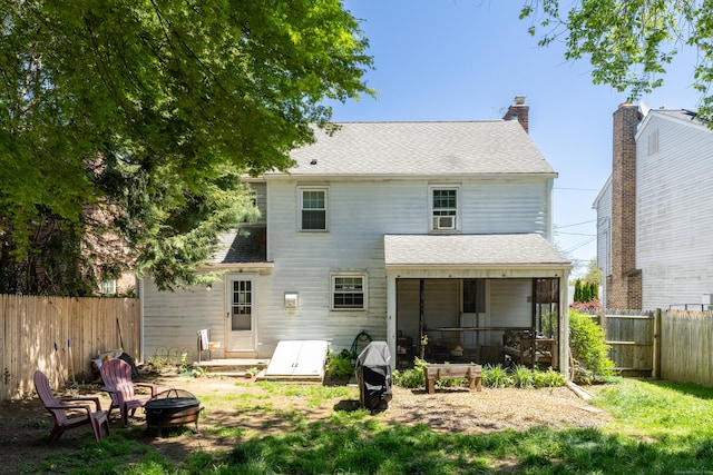 rear view of house with fence private yard, a shingled roof, and an outdoor fire pit