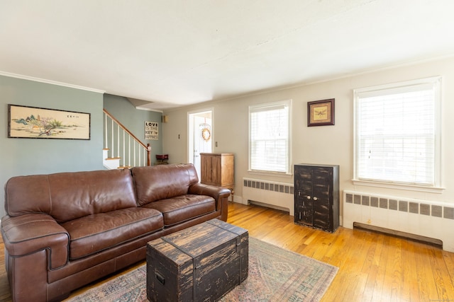 living room with stairway, ornamental molding, radiator, and light wood-style floors