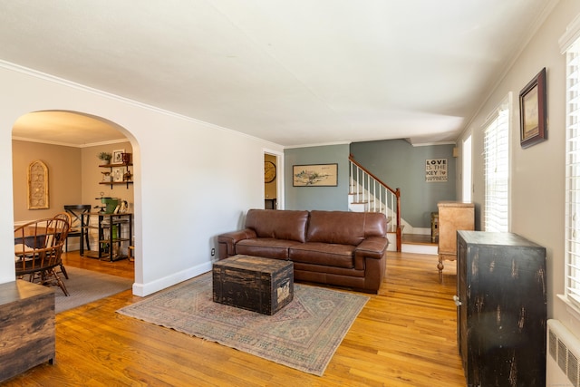 living area with stairs, arched walkways, radiator heating unit, and light wood finished floors