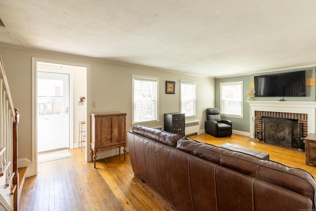 living area with radiator heating unit, hardwood / wood-style flooring, and a healthy amount of sunlight