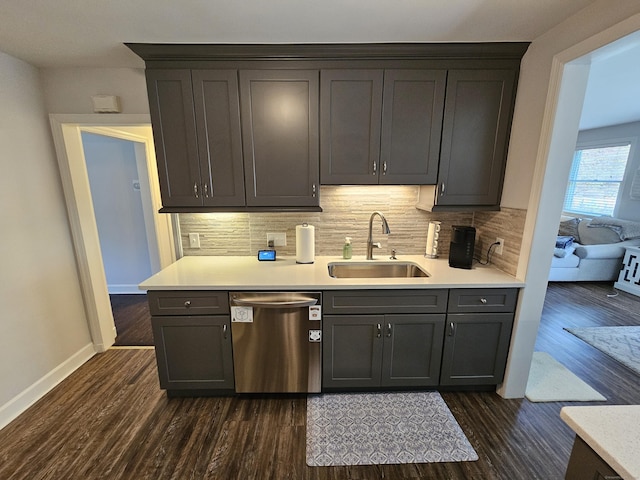 kitchen with stainless steel dishwasher, a sink, decorative backsplash, light countertops, and dark wood-style floors