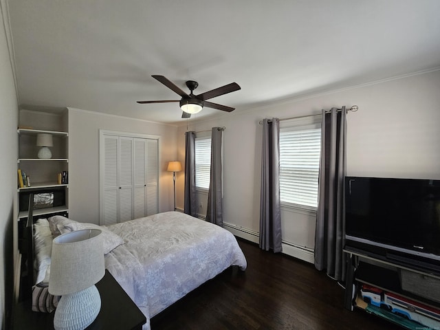 bedroom with a baseboard heating unit, a closet, ornamental molding, and dark wood finished floors