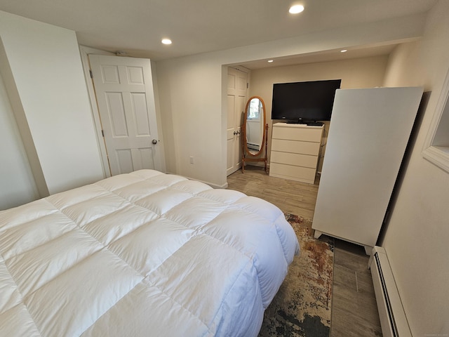 bedroom featuring a baseboard heating unit, wood finished floors, and recessed lighting