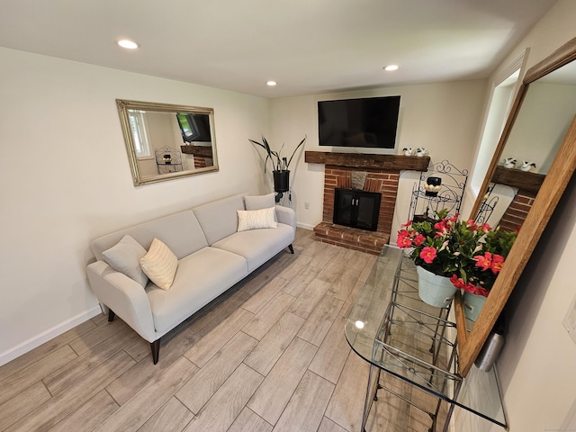 living area featuring light wood-style flooring, a brick fireplace, and recessed lighting