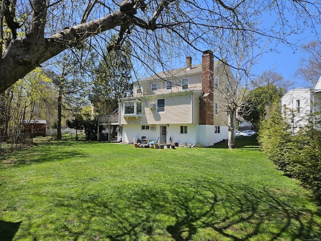 back of house with a chimney, a wooden deck, a yard, and stairs