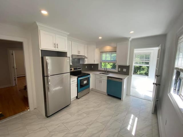 kitchen featuring stainless steel appliances, a sink, white cabinetry, decorative backsplash, and under cabinet range hood