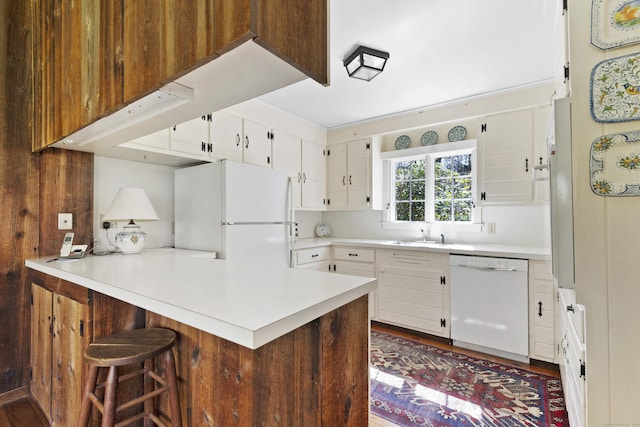538 County Rd, Guilford, CT 06437 - kitchen with light countertops, white cabinets, a peninsula, a breakfast bar, and white appliances