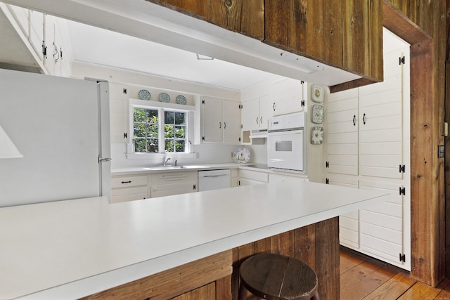 538 County Rd, Guilford, CT 06437 - kitchen with wood finished floors, light countertops, a sink, white appliances, and white cabinetry