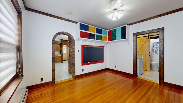8 Kent St, Plainville, CT 06062 - unfurnished room featuring arched walkways, wood finished floors, a barn door, baseboards, and a baseboard radiator
