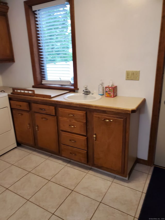 8 Kent St, Plainville, CT 06062 - kitchen with a sink, light tile patterned flooring, light countertops, washer / clothes dryer, and brown cabinetry
