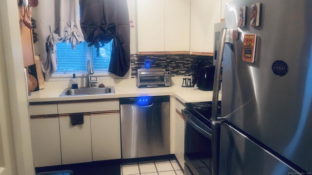 kitchen featuring a sink, a toaster, stainless steel appliances, white cabinetry, and light countertops