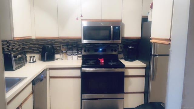 kitchen with white cabinetry, light countertops, stainless steel appliances, and decorative backsplash