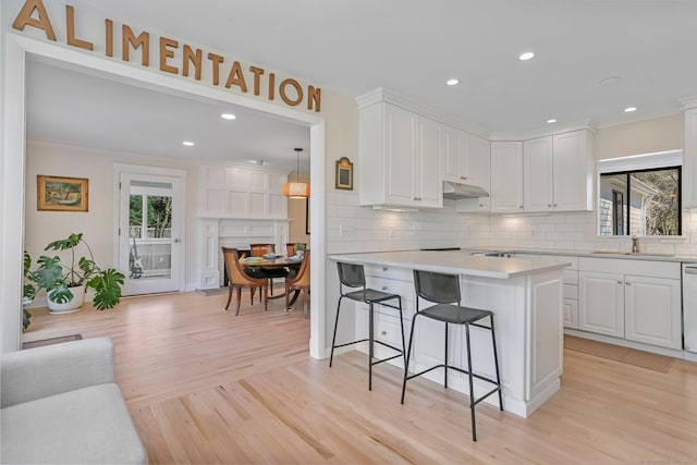 2 Donald Dr, Westport, CT 06880 - kitchen with under cabinet range hood, a kitchen bar, light countertops, backsplash, and white cabinets