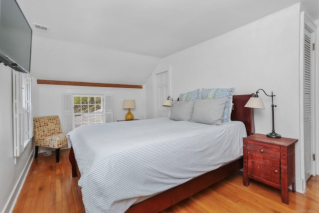 bedroom with visible vents, baseboards, lofted ceiling, and hardwood / wood-style flooring