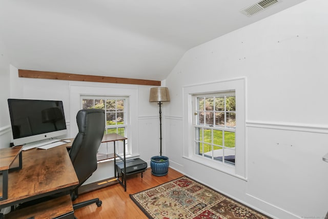 home office with a healthy amount of sunlight, vaulted ceiling, wood finished floors, and visible vents