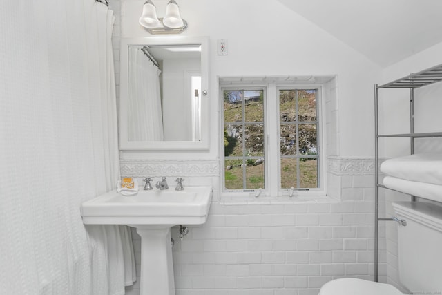 full bath featuring lofted ceiling, toilet, and a wainscoted wall