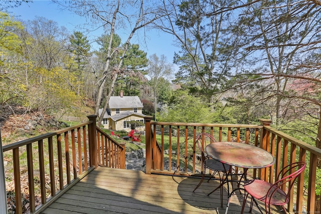 wooden terrace featuring an outbuilding and outdoor dining area