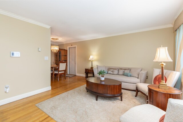 living room with ornamental molding, baseboards, a notable chandelier, and wood finished floors