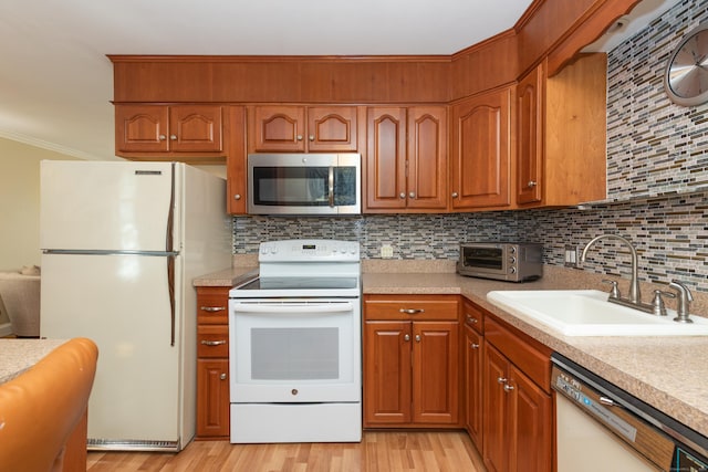 kitchen featuring a sink, a toaster, tasteful backsplash, white appliances, and light countertops