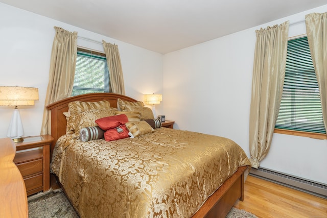 bedroom featuring baseboard heating and wood finished floors