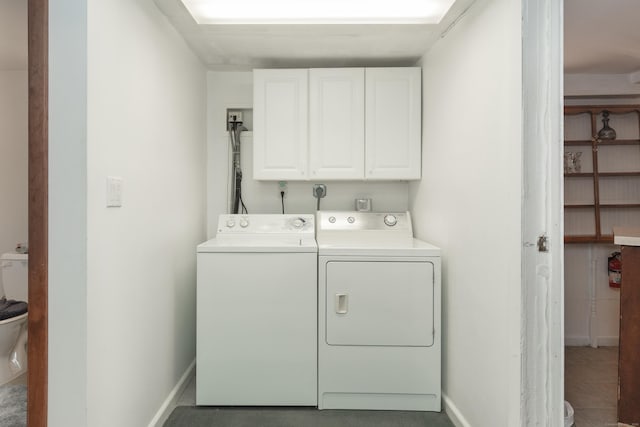 laundry area with tile patterned flooring, baseboards, washer and clothes dryer, and cabinet space
