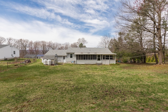 rear view of house featuring roof with shingles, a sunroom, fence, and a yard