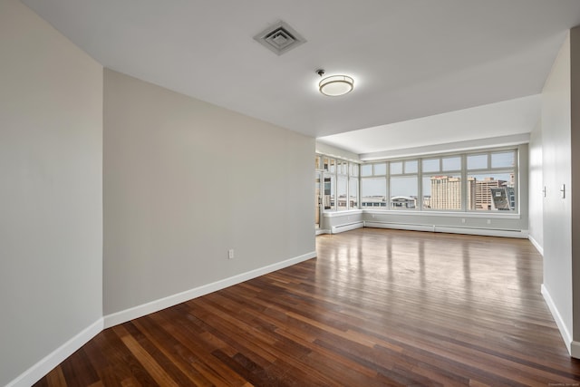 spare room featuring dark wood-style floors, visible vents, baseboards, and a baseboard radiator
