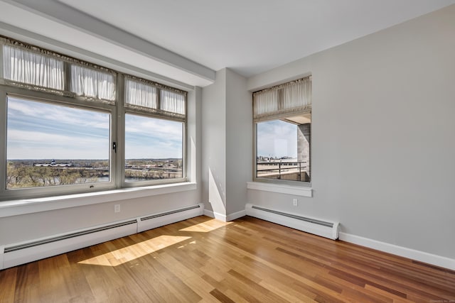 spare room featuring baseboards, wood finished floors, and a baseboard radiator