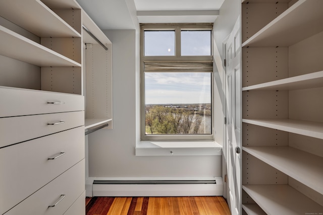 walk in closet with wood finished floors and baseboard heating