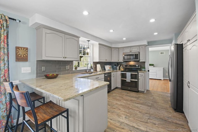8 Gregory Ln, Simsbury, CT 06070 - kitchen featuring a sink, stainless steel appliances, light wood-type flooring, a peninsula, and backsplash