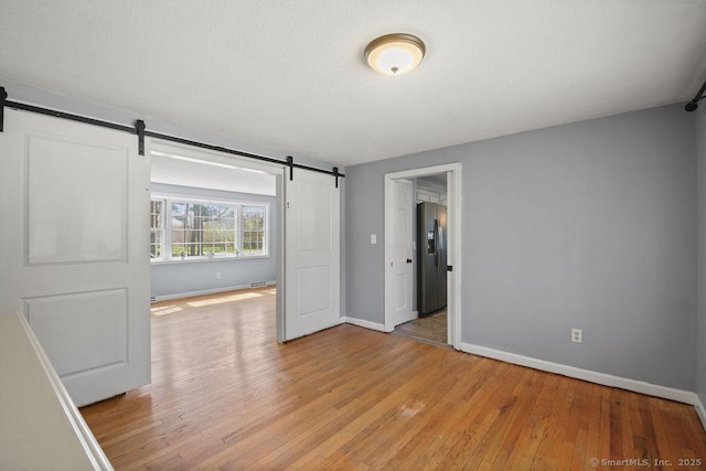 8 Gregory Ln, Simsbury, CT 06070 - unfurnished room with baseboards, a barn door, and light wood-type flooring