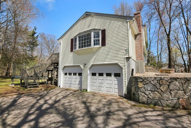 8 Gregory Ln, Simsbury, CT 06070 - view of property exterior featuring a chimney, stairway, a garage, and driveway