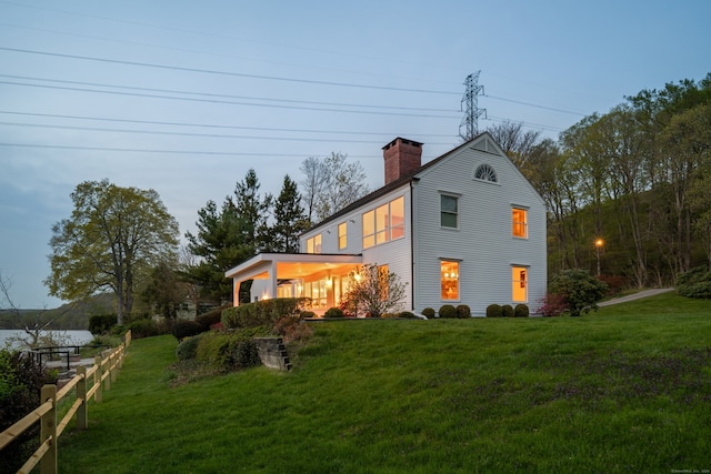 back of house featuring a lawn and a chimney