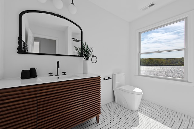 bathroom featuring vanity, baseboards, toilet, and visible vents