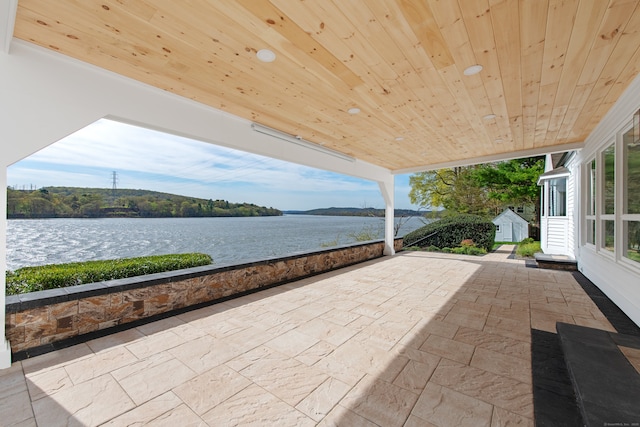 view of patio / terrace with an outbuilding, a storage shed, and a water view