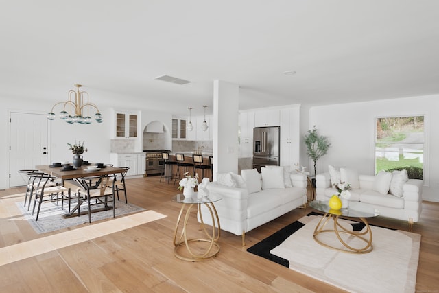 living room with visible vents, light wood-style floors, and a notable chandelier