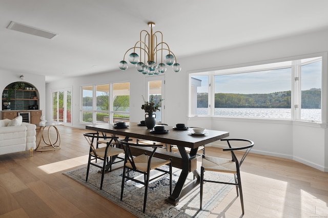 dining room featuring baseboards, a notable chandelier, light wood finished floors, and visible vents